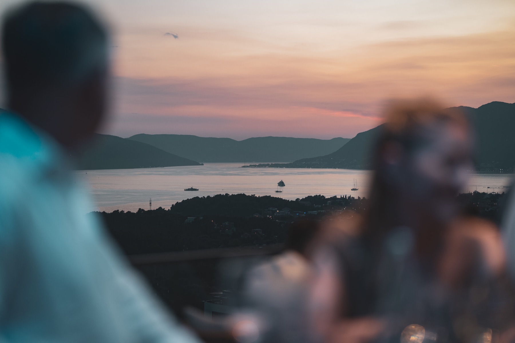 Sunset over the Bay of Kotor seen from Cielo Rooftop, with residents softly out of focus