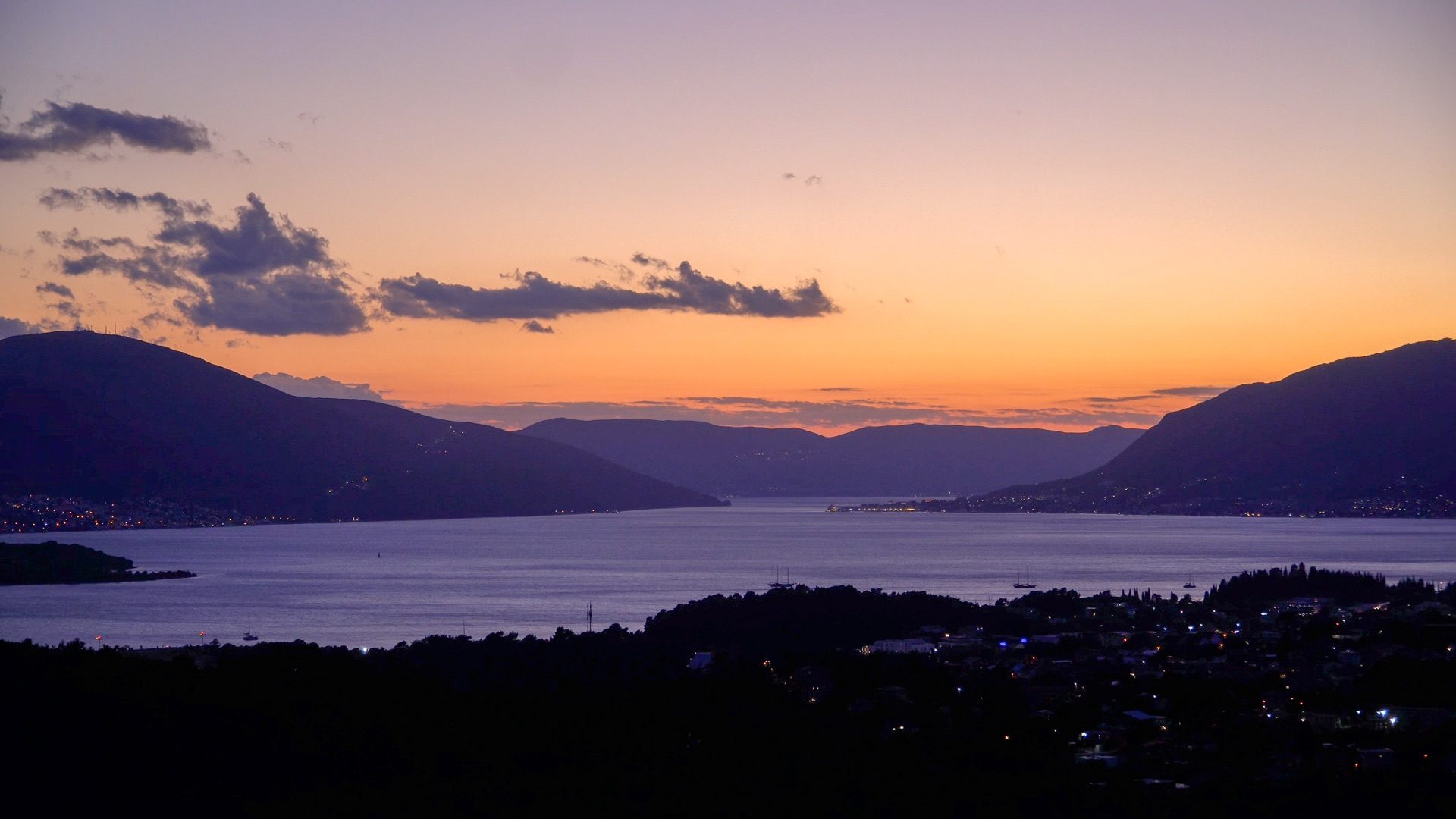 Sunset over the Bay of Kotor from Kavač, with mountain silhouettes and town lights